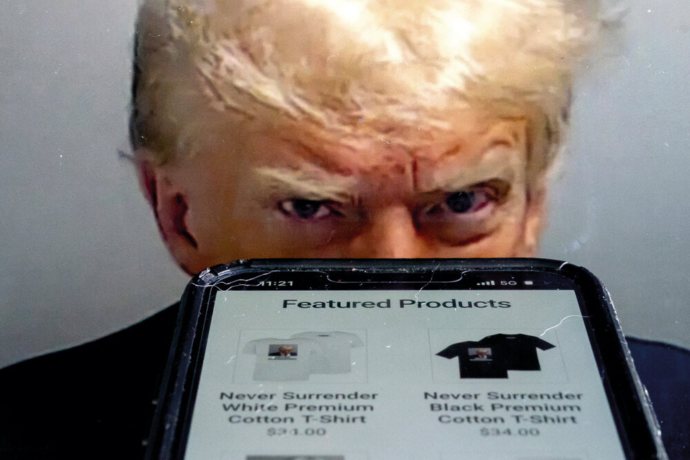 Trump Save America es un comité web que vende productos en apoyo a la candidatura presidencial de Donald Trump para 2024. De fondo, la fotografía policial del arresto en Georgia que se viralizó junto con el anuncio de la fecha del juicio. Foto: AFP