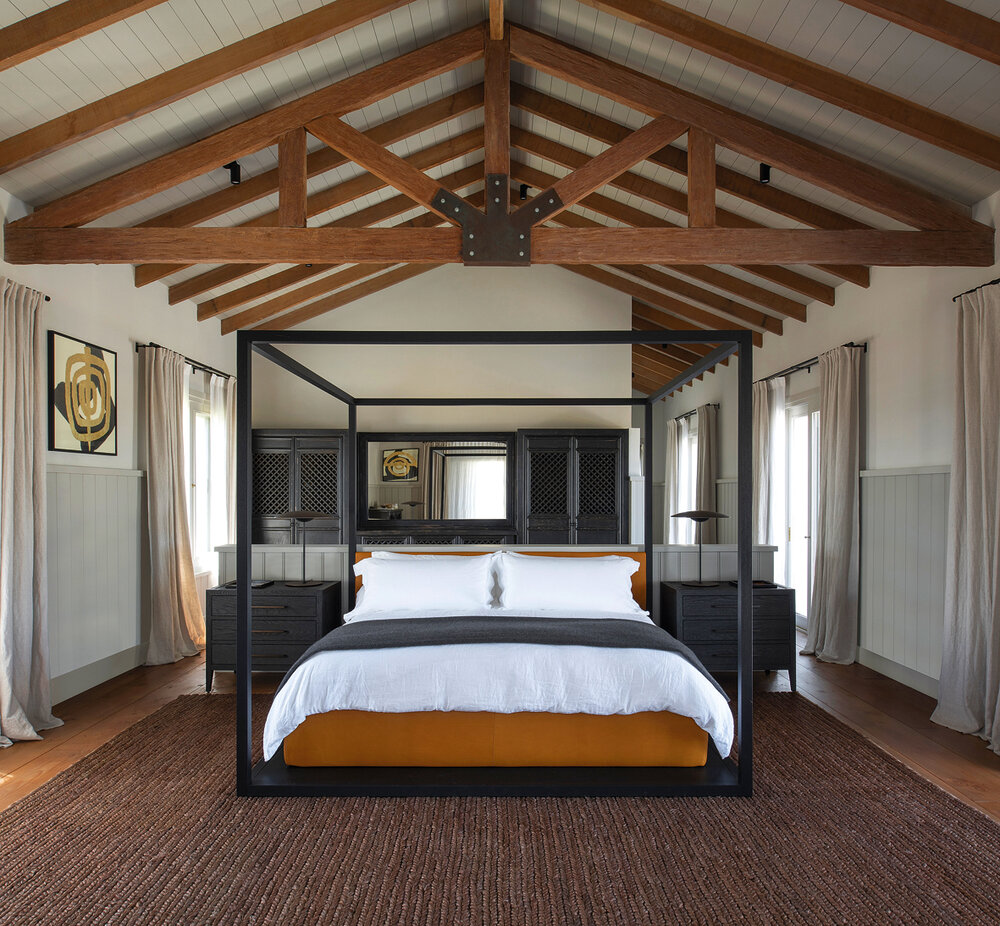 <em>La cama con baldaquino de madera, de Max Alto, tapizada en cuero se acompaña de una mesa de luz de roble de RH, velador es Ginger de Marsett, alfombra de Ralph Lauren. </em>