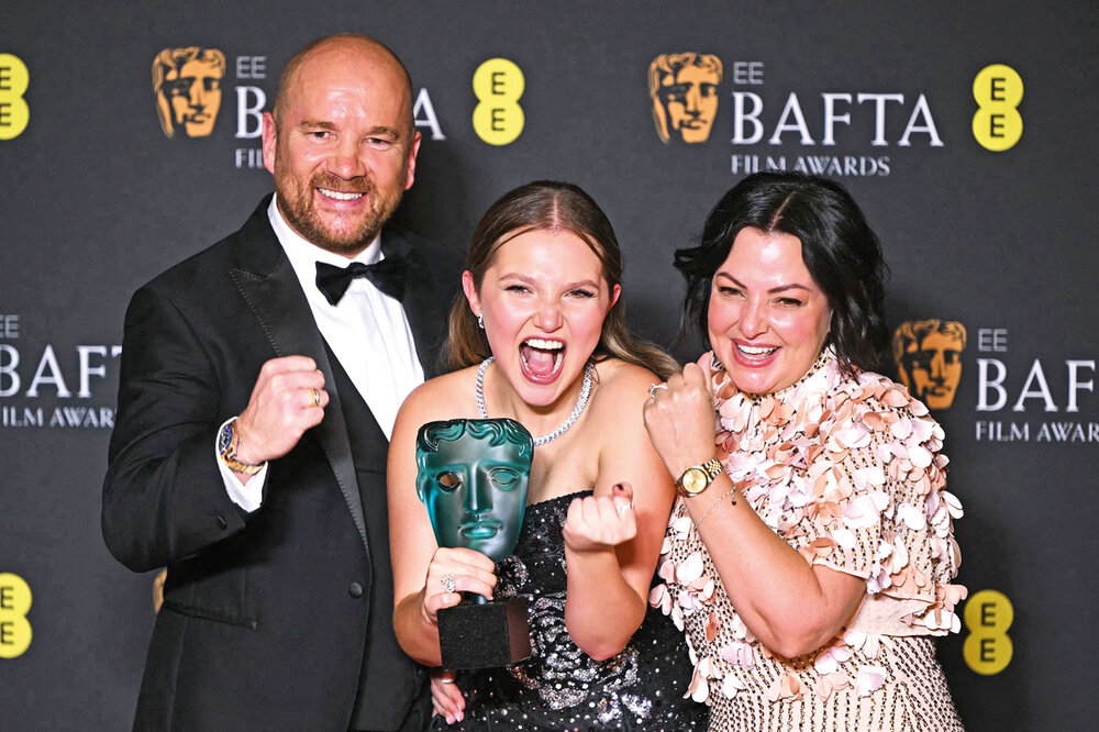 La actriz británica Mia McKenna-Bruce celebró con sus padres el premio a estrella en ascenso en los Bafta. AFP